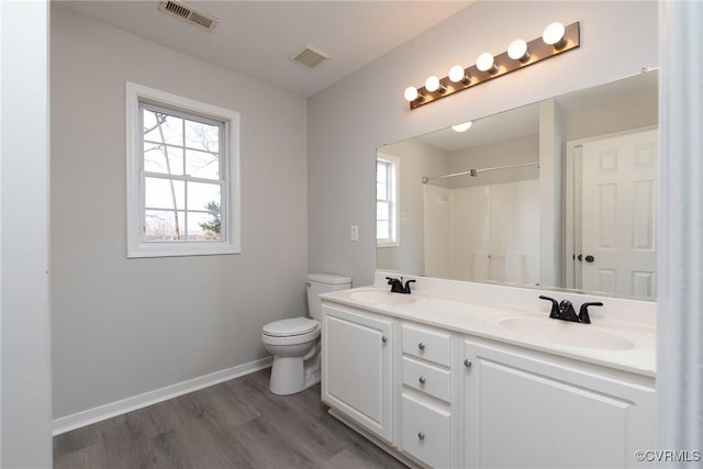 bathroom featuring a shower, hardwood / wood-style floors, vanity, and toilet