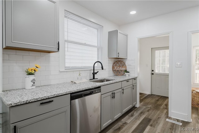 kitchen featuring light stone counters, sink, dishwasher, hardwood / wood-style floors, and gray cabinets