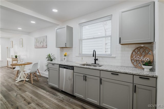 kitchen featuring tasteful backsplash, gray cabinetry, sink, wood-type flooring, and dishwasher