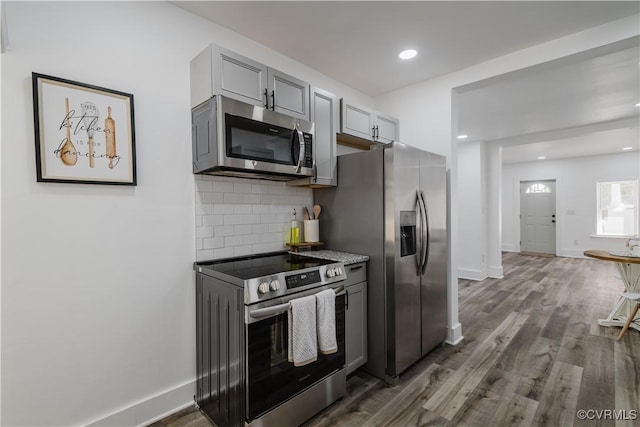 kitchen with backsplash, gray cabinetry, dark wood-type flooring, and appliances with stainless steel finishes