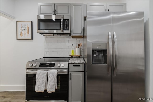 kitchen featuring backsplash, dark hardwood / wood-style floors, gray cabinets, and stainless steel appliances