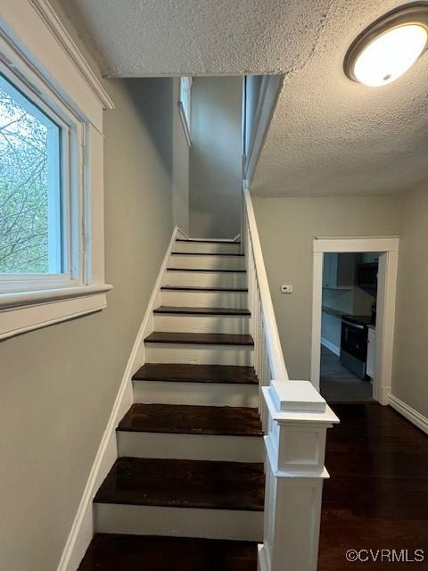 stairs with a textured ceiling and hardwood / wood-style flooring