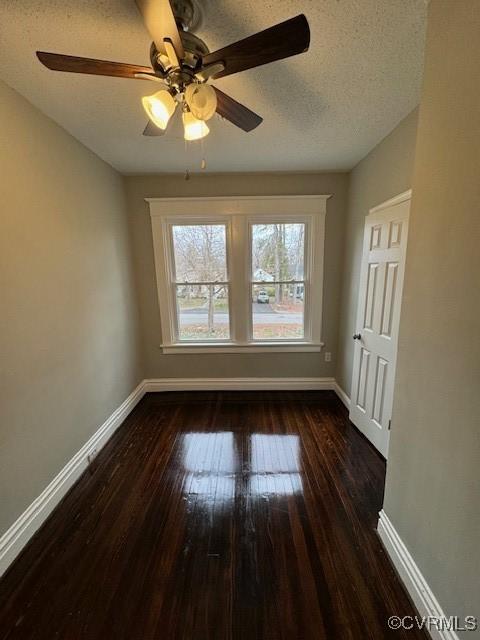 empty room featuring ceiling fan, dark hardwood / wood-style flooring, and a textured ceiling