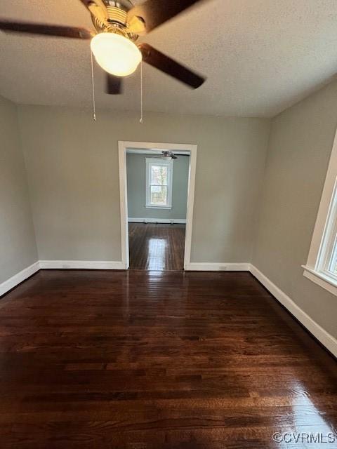 empty room with ceiling fan, dark hardwood / wood-style flooring, and a textured ceiling