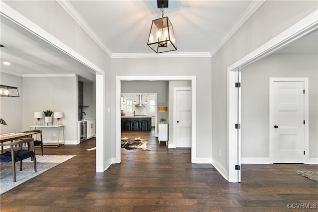 entrance foyer featuring dark wood-type flooring, an inviting chandelier, and crown molding