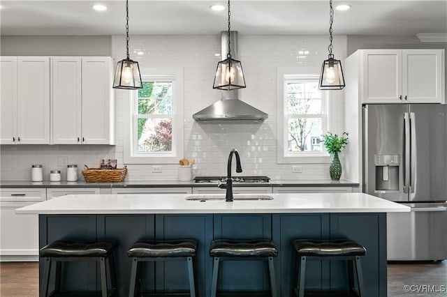 kitchen with white cabinetry, a kitchen island with sink, decorative light fixtures, and appliances with stainless steel finishes