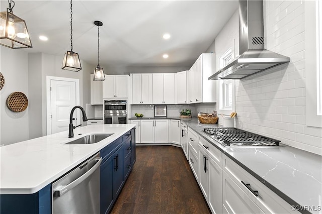 kitchen with white cabinets, decorative light fixtures, stainless steel appliances, and wall chimney range hood