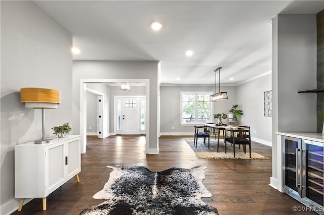 entryway with dark hardwood / wood-style floors, ornamental molding, and beverage cooler