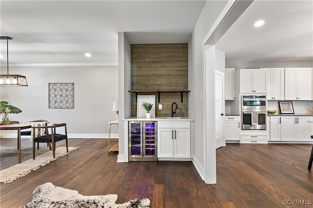 bar featuring pendant lighting, stainless steel double oven, white cabinetry, and wine cooler