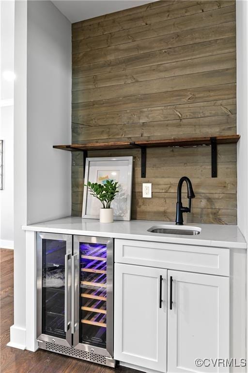 bar featuring wood walls, white cabinetry, sink, and wine cooler