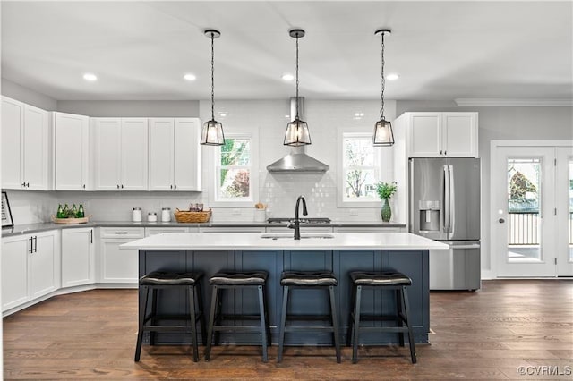 kitchen featuring white cabinets, stainless steel fridge with ice dispenser, a center island with sink, and a kitchen breakfast bar