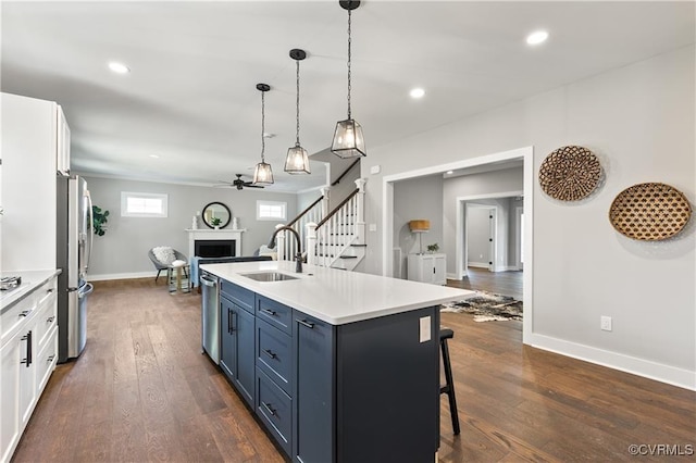 kitchen with white cabinetry, sink, blue cabinets, decorative light fixtures, and appliances with stainless steel finishes