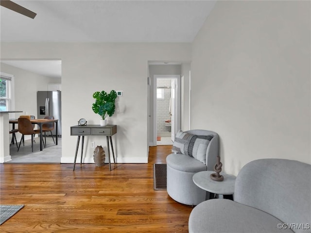 living area featuring wood-type flooring, ceiling fan, and a healthy amount of sunlight