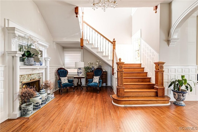 stairs featuring a premium fireplace, wood-type flooring, a notable chandelier, and high vaulted ceiling