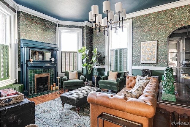 living room featuring crown molding, a chandelier, radiator heating unit, a tile fireplace, and hardwood / wood-style floors