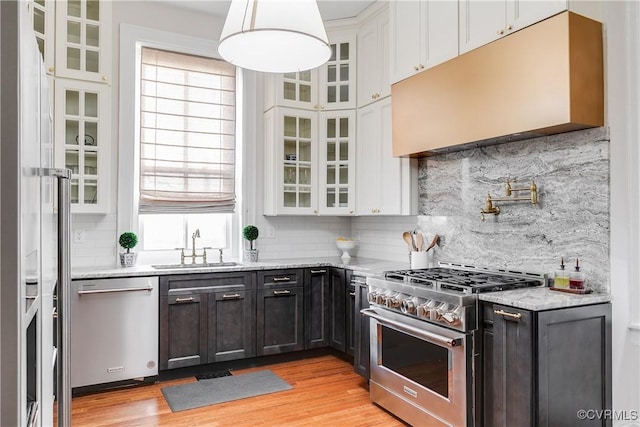 kitchen featuring appliances with stainless steel finishes, white cabinetry, sink, backsplash, and light wood-type flooring