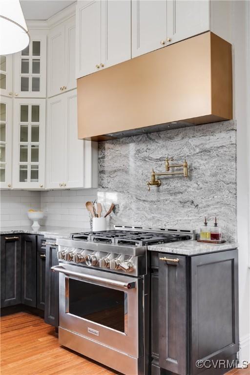 kitchen featuring white cabinetry, backsplash, light hardwood / wood-style floors, and gas stove