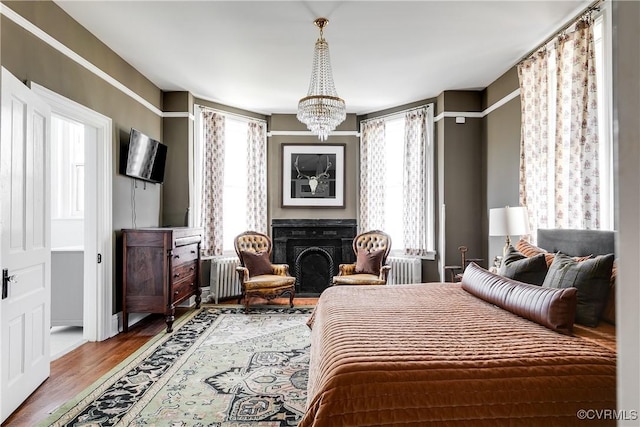 bedroom with a chandelier, radiator, and hardwood / wood-style floors