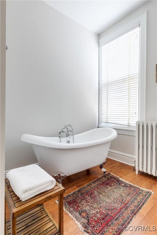 bathroom featuring a bath, radiator, and hardwood / wood-style floors