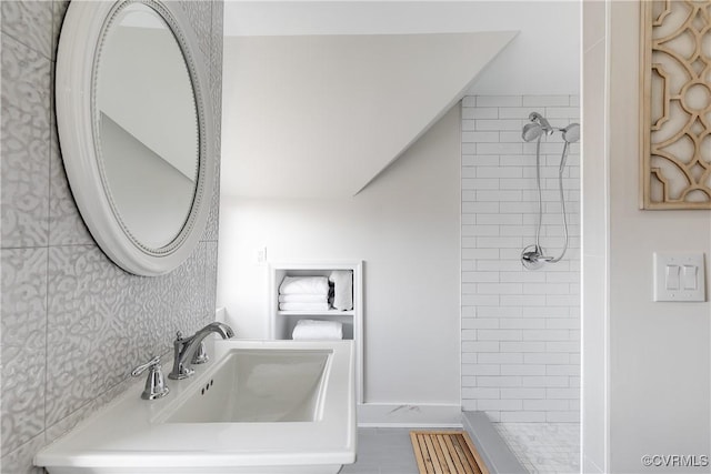 bathroom with tiled shower and sink