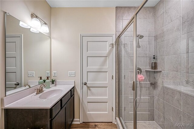 bathroom with hardwood / wood-style flooring, vanity, and walk in shower