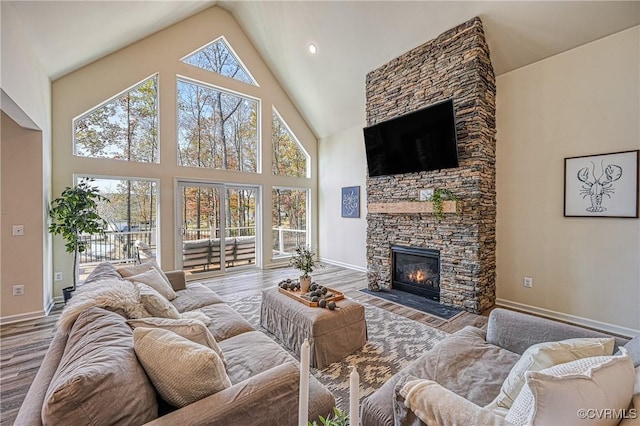 living room featuring high vaulted ceiling, a stone fireplace, and hardwood / wood-style floors