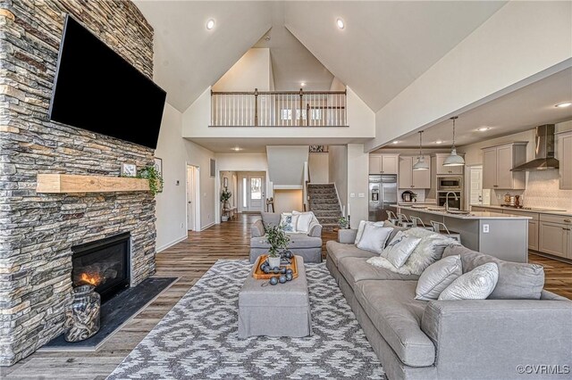 living room featuring a stone fireplace, sink, high vaulted ceiling, and dark hardwood / wood-style floors