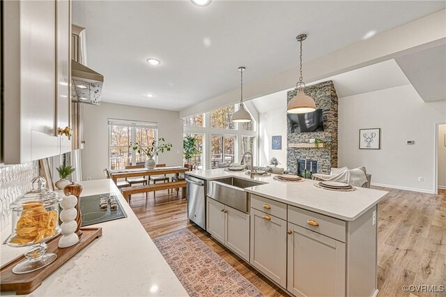 kitchen featuring a fireplace, gray cabinetry, sink, decorative light fixtures, and dishwasher