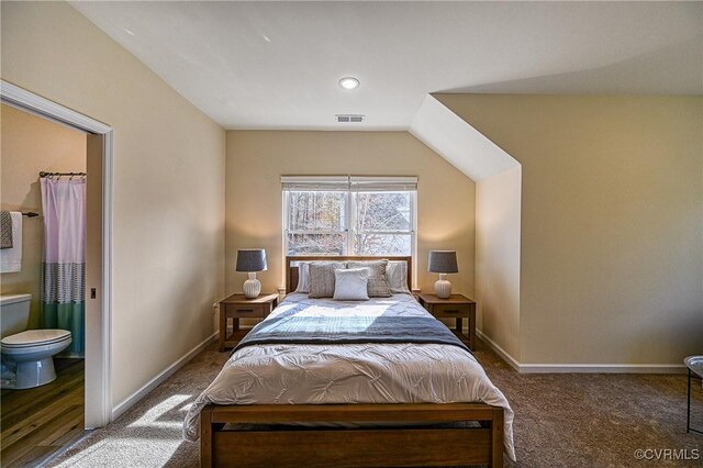 carpeted bedroom with vaulted ceiling and ensuite bath