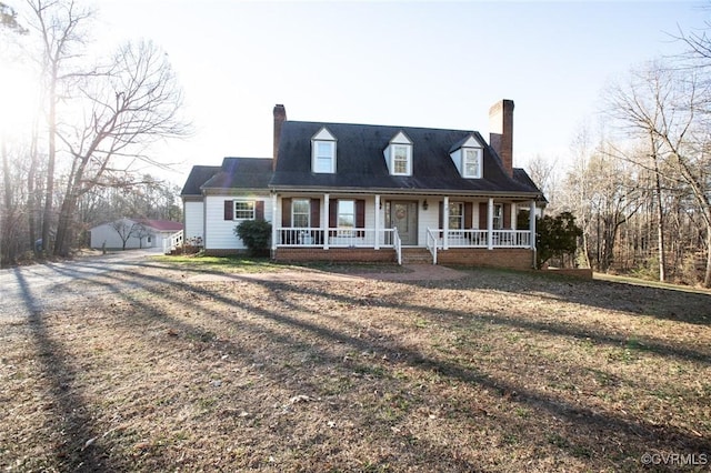 cape cod home with a porch, a garage, an outdoor structure, and a front lawn