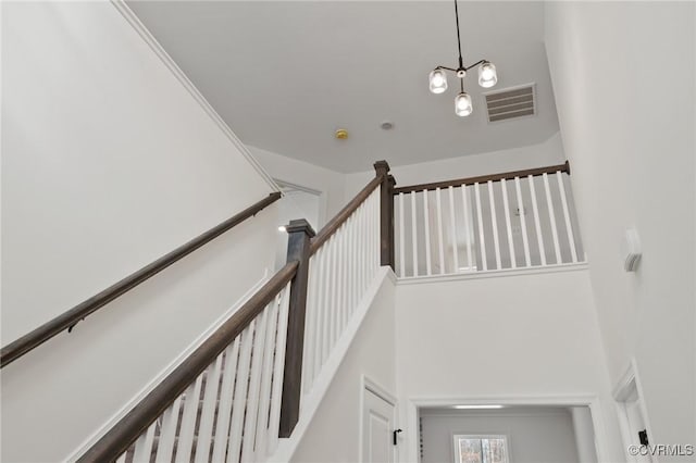 stairway with a towering ceiling and a notable chandelier