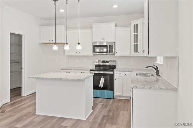 kitchen with light stone countertops, appliances with stainless steel finishes, sink, a center island, and white cabinetry