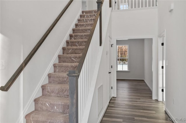 stairway featuring a high ceiling and hardwood / wood-style flooring