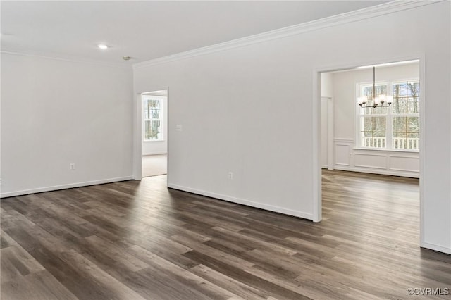 spare room with dark hardwood / wood-style flooring, an inviting chandelier, and crown molding