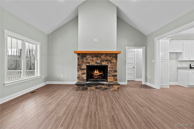 unfurnished living room featuring light hardwood / wood-style floors, a stone fireplace, and lofted ceiling