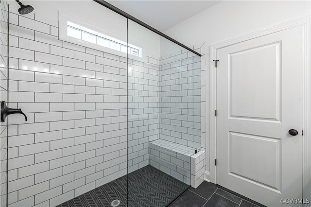 bathroom with a tile shower and tile patterned flooring