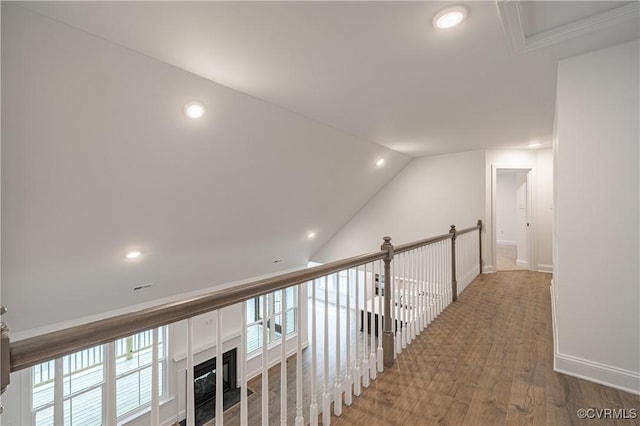 hall with wood-type flooring and vaulted ceiling