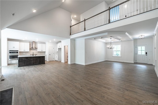 unfurnished living room featuring a chandelier, a high ceiling, and dark wood-type flooring