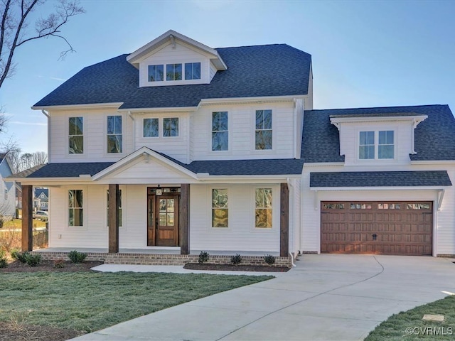 view of front of property featuring a front yard, a porch, and a garage