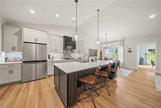 kitchen with stainless steel appliances, tasteful backsplash, an island with sink, pendant lighting, and a breakfast bar