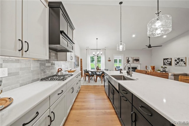 kitchen with light stone countertops, hanging light fixtures, backsplash, ceiling fan with notable chandelier, and appliances with stainless steel finishes