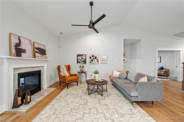 living room with hardwood / wood-style flooring, ceiling fan, lofted ceiling, and a premium fireplace