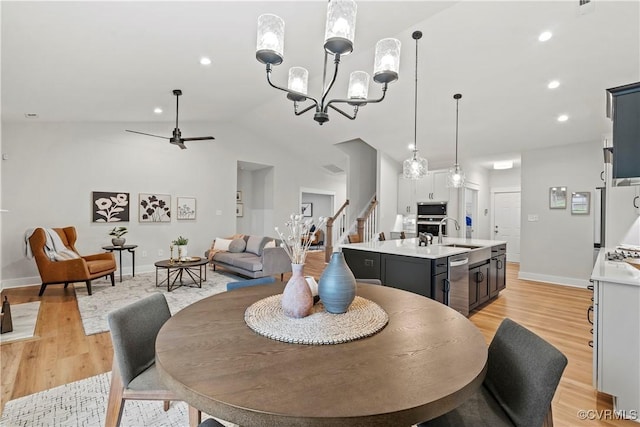 dining area featuring ceiling fan with notable chandelier, lofted ceiling, sink, and light hardwood / wood-style flooring