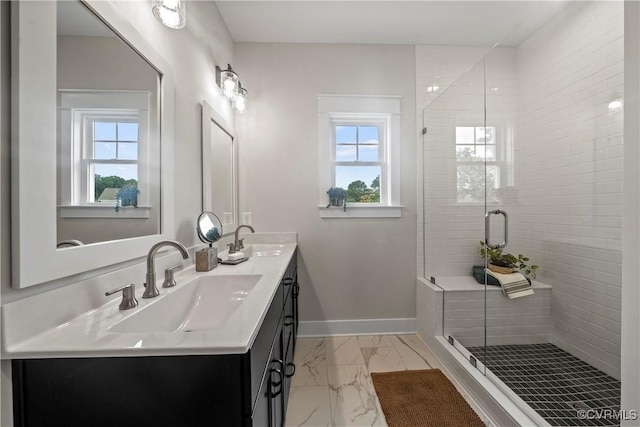 bathroom with vanity, a shower with door, and a healthy amount of sunlight