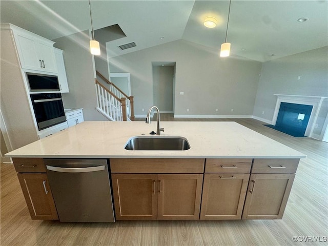 kitchen with stainless steel appliances, a sink, open floor plan, hanging light fixtures, and lofted ceiling