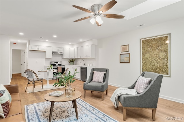 living room featuring light hardwood / wood-style flooring, ceiling fan, and sink