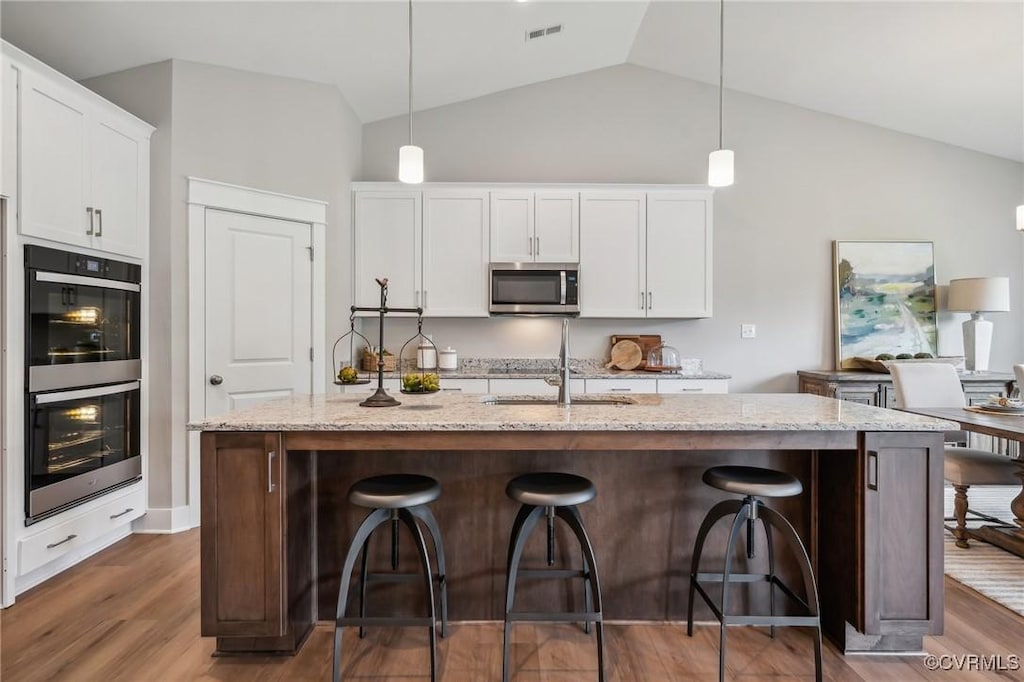 kitchen featuring appliances with stainless steel finishes, pendant lighting, and an island with sink