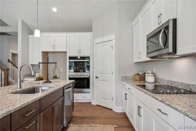 kitchen featuring stainless steel appliances, white cabinetry, hanging light fixtures, and sink