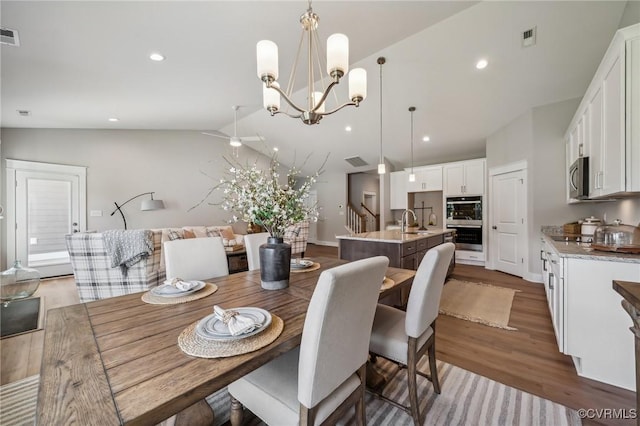 dining room with dark hardwood / wood-style floors, lofted ceiling, sink, and a chandelier