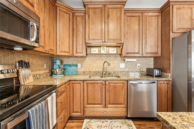 kitchen featuring light stone counters, sink, decorative backsplash, and stainless steel appliances